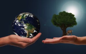 uma mão está segurando o planeta terra e outra mão está segurando uma árvore e um animal (natureza)